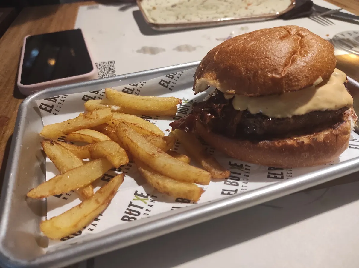 Hamburguesa en pan brioche con patatas, sobre bandeja con papel de El Butxe