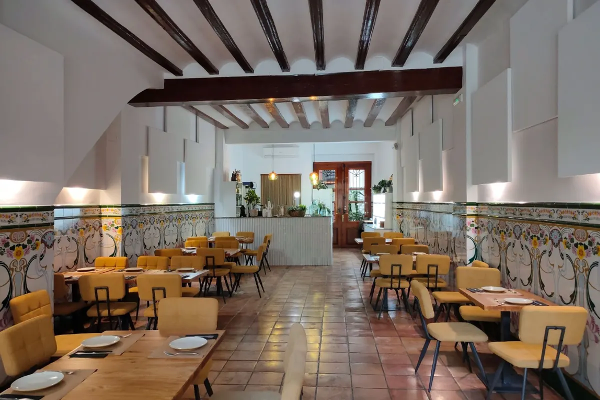 Nuestro comedor: vigas de madera, zócalo de azulejo pintado, sillas mostaza y suelo de barro cocido