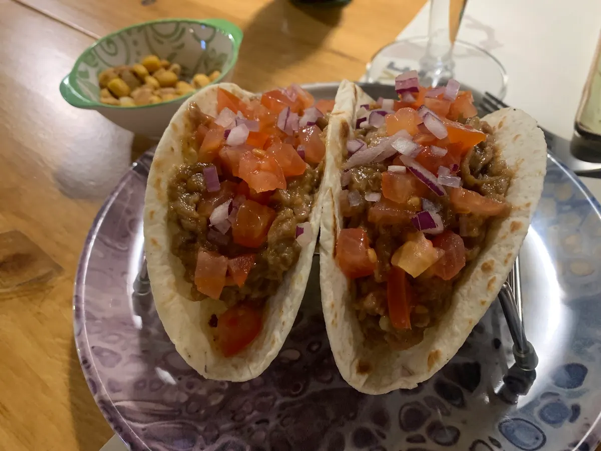 Dos tacos con carne, tomate y cebolla morada